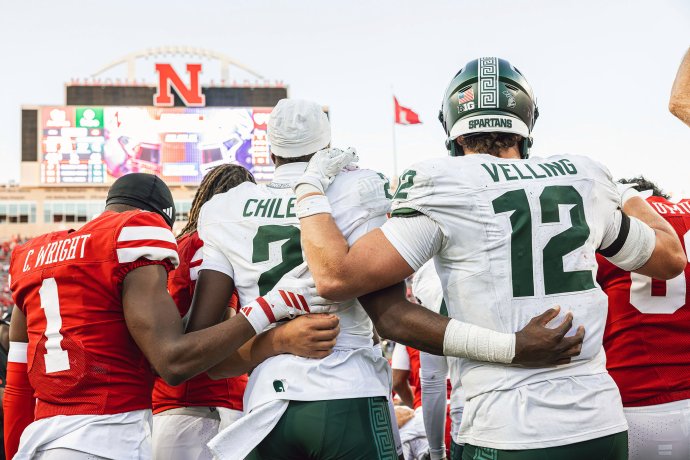 Nebraska and Michigan State players gather in a huddle for a postgame prayer at Memorial Stadium.