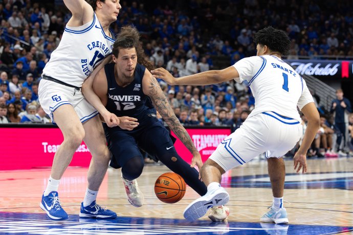 Xavier forward Tre Carroll loses control of the ball while driving between Creighton defenders.