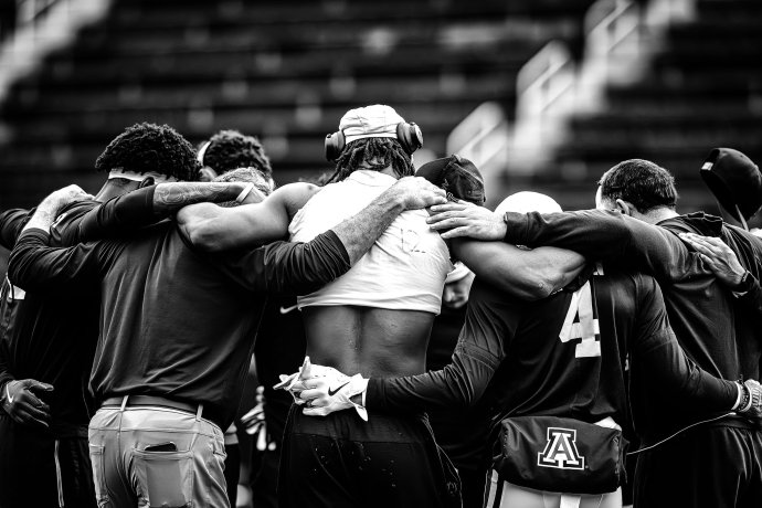 Arizona Wildcats players and staff gather in a huddle during pregame warmups at Nippert Stadium.