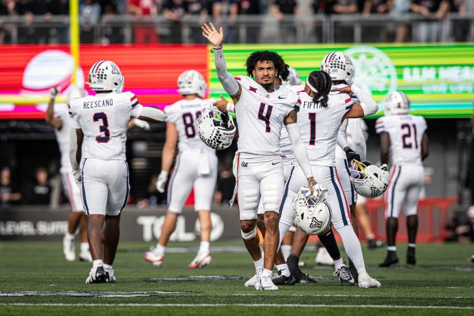 Arizona Wildcats players wave toward Cincinnati fans from the field following the game.