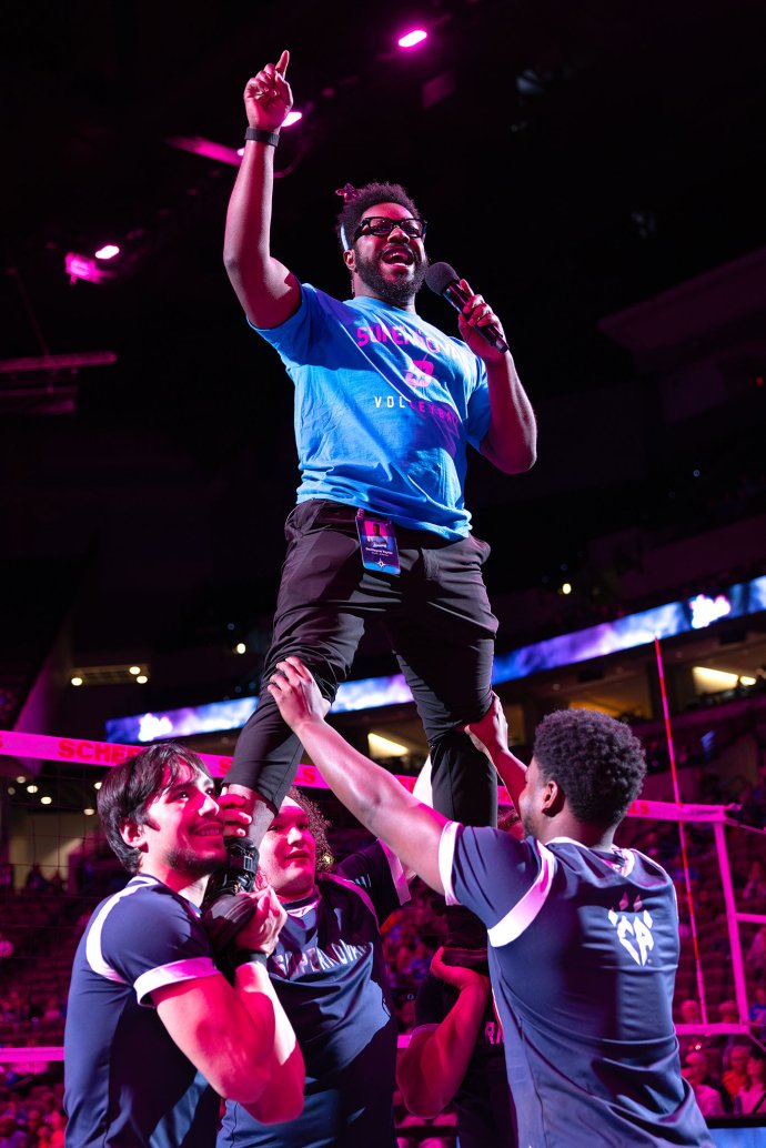 Omaha Supernovas emcee Dewyen Taylor raises a hand while speaking into a microphone during Blue Out festivities.
