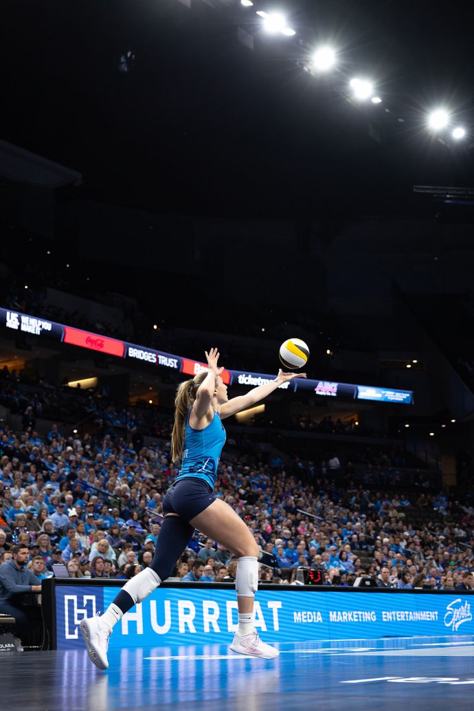 Kiara Reinhardt (10) steps into a serve with the crowd filling the stands behind her.