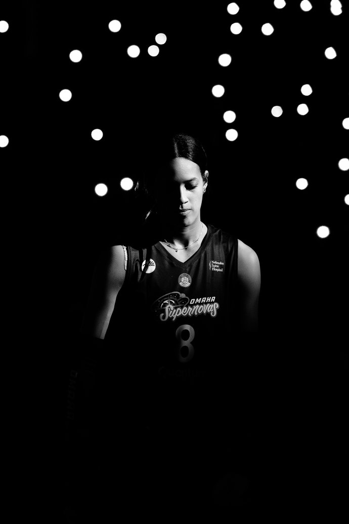 Omaha Supernovas outside hitter Reagan Cooper (8) stands during pregame introductions with spectators’ phone lights glowing behind her.