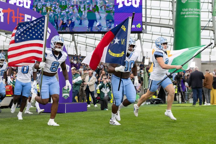 North Carolina players exit the tunnel as punter Adam McCann-Gibbs carries the Irish tricolor onto the field at Aviva Stadium.