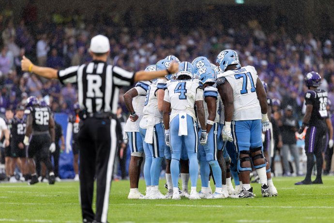 North Carolina players huddle on the field in the rain at Aviva Stadium.